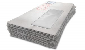 A stack of regular white envelopes with delivery stamps and a clear window on an isolated white background