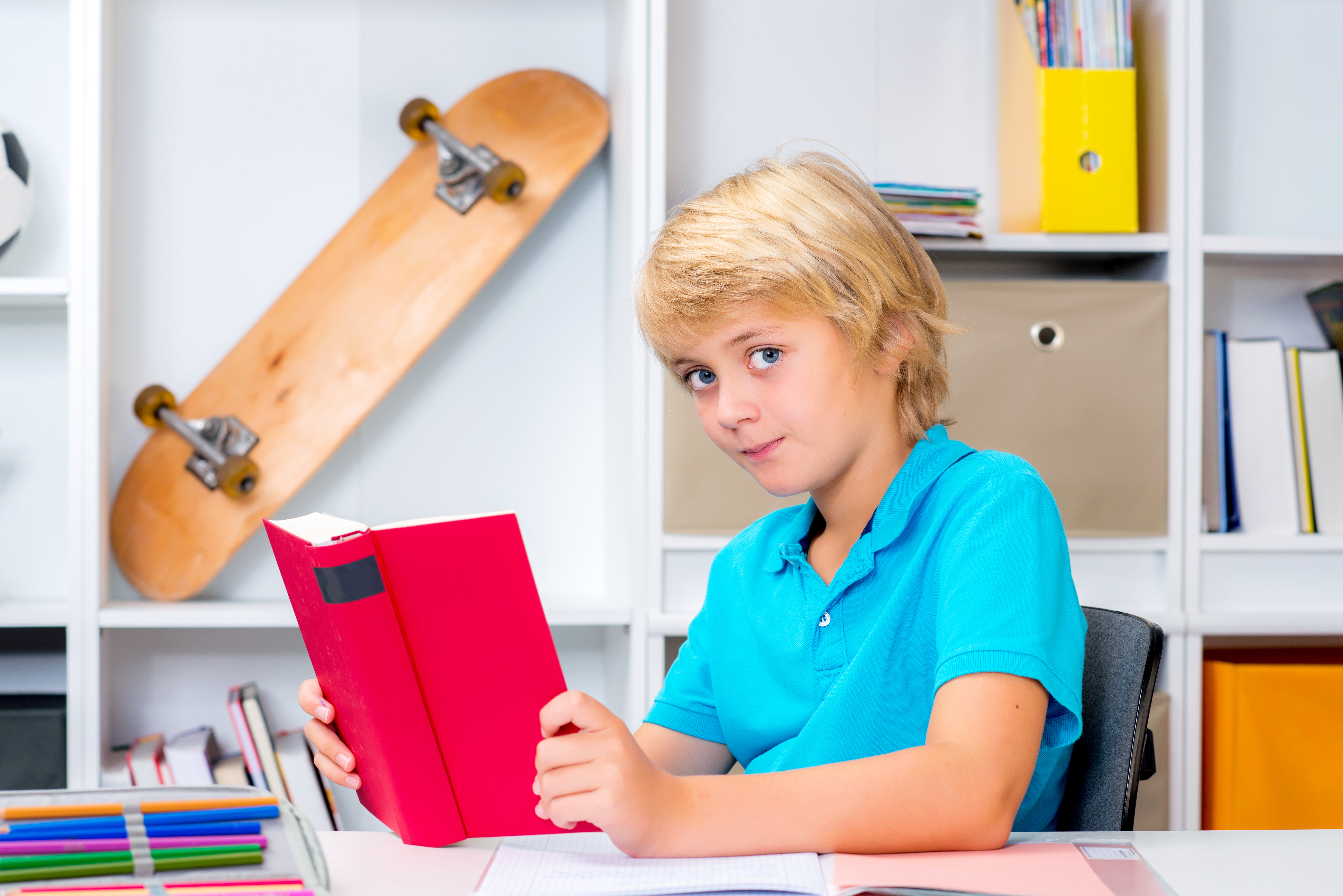 blond boy doing homework and reading a book